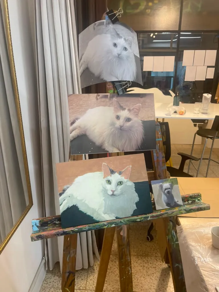 A finished painting of a white cat beside the reference photos, from a Paint Your Pet workshop