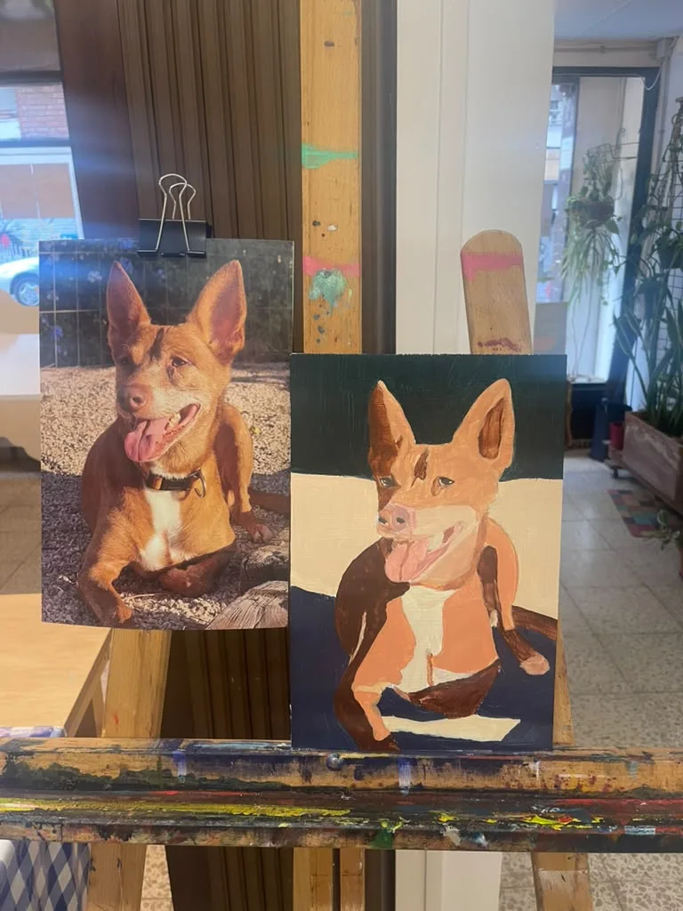 A finished painting of a ginger dog with big ears, beside the owner’s photo.