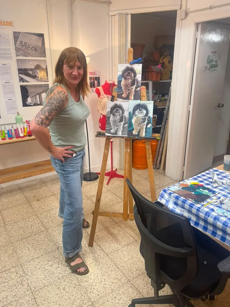 The owner standing beside the easel with the finished shih tzu paintings.