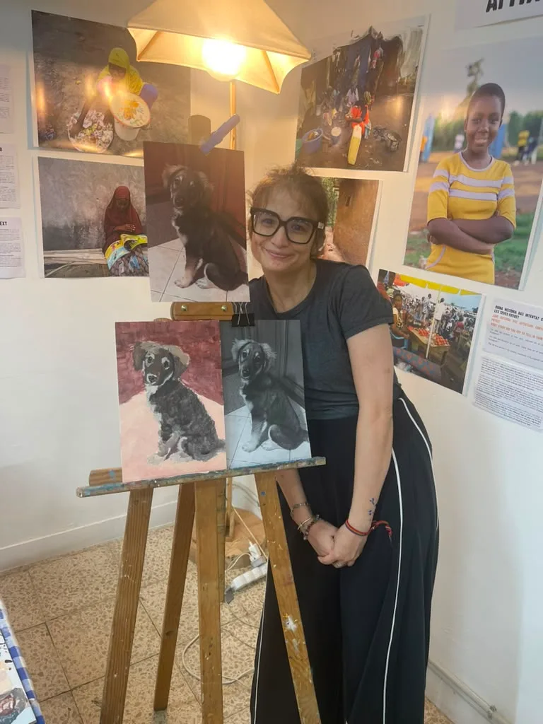 The owner smiling beside the finished puppy painting and its reference.